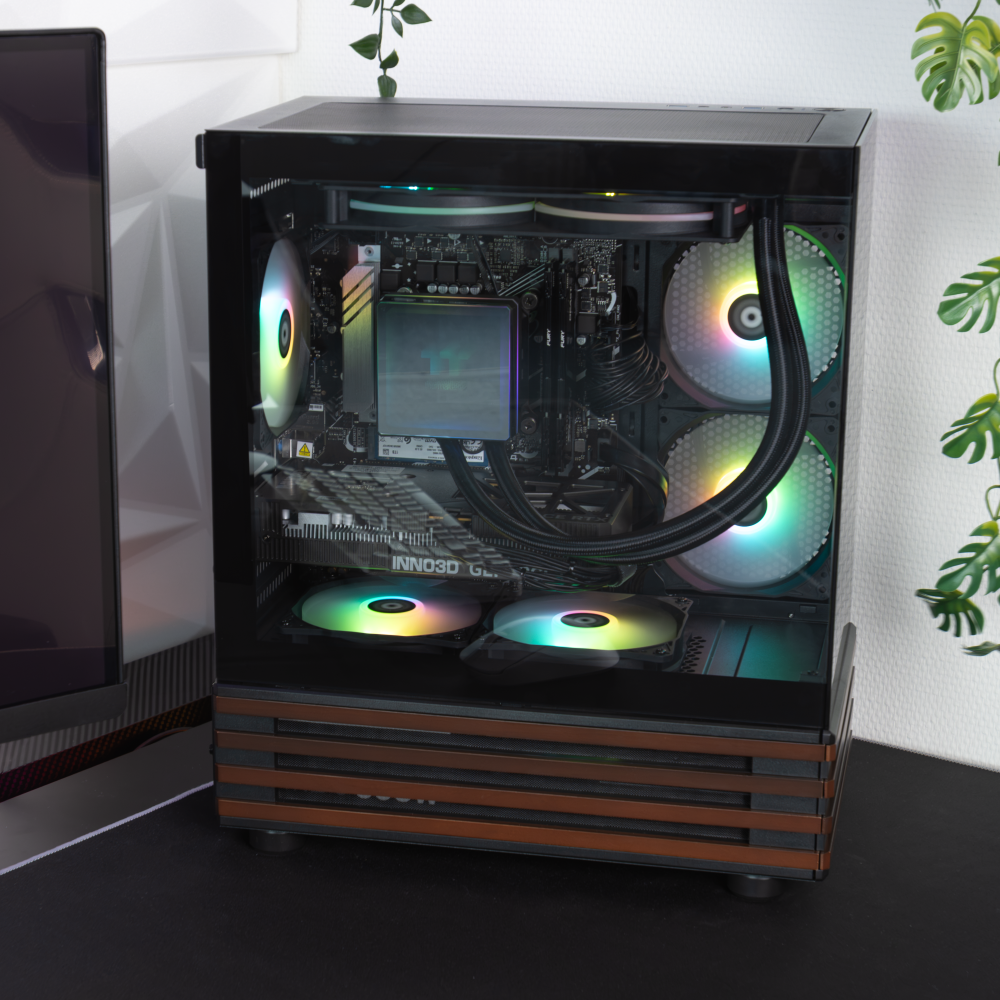 Quasit 5060 Black LCGS Gaming PC in einem Lifesylebild mit View 170 WS Black Gehäuse, Panoramaglas, ARGB-Beleuchtung und Holzakzenten.
